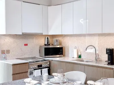 a kitchen with white cabinets and a stove and a sink at Amazing 1 Bedroom in Burj Royale Downtown in Dubai