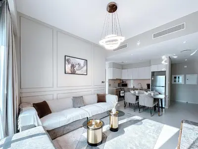 a living room with a white couch and a kitchen at Amazing 1 Bedroom in Burj Royale Downtown in Dubai