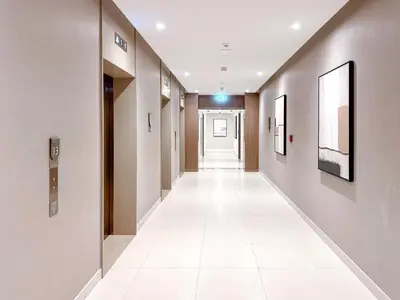 a hallway of a hospital with white tile floors and walls at Amazing 1 Bedroom in Burj Royale Downtown in Dubai