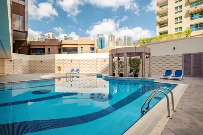 a swimming pool with two blue chairs next to a building at Stylish Marina View Apartment With Private Marina Walk Access in Dubai