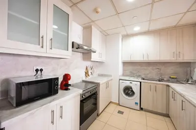 a kitchen with white cabinets and a microwave at Cozy Dubai Eye & Sunset Views - JBR Beachfront - Gym & Pool - Free Parking in Dubai