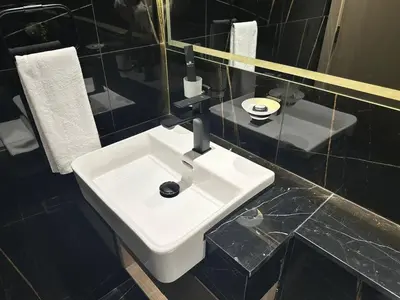 a white sink in a bathroom with black tiles at Comfortable 1br In Jvc Balcony Free Parking in Dubai