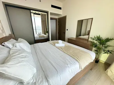 a bedroom with a large white bed and a mirror at Modern 1br In Jvc Balcony, Pool & Parking in Dubai