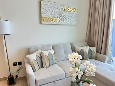 a living room with a couch and a vase with flowers at Modern 1br In Jvc Balcony, Pool & Parking in Dubai