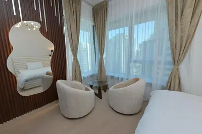 a bedroom with two chairs and a bed and a window at La Vista Holiday Home with burj khalifa & fountain view in Dubai