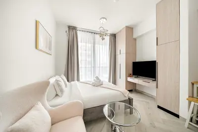 a bedroom with a bed and a couch and a tv at Cozy Studio in Empire Residence in Dubai