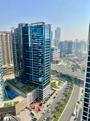 a tall blue building in a city with a highway at Luxury Studio Near Burj Khalifa in Dubai