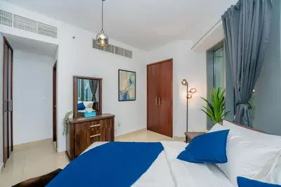 a bedroom with a blue and white bed and a mirror at King 1BR Apartment With Burj Khalifa & Fountain View in Dubai