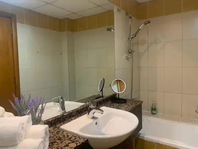 a bathroom with a sink and a mirror and a tub at Cozy home marina in Dubai