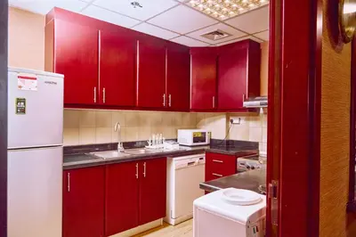 a kitchen with red cabinets and a white refrigerator at ROYAL BEACH RESiDENCES 1 in Dubai
