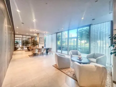 a living room with white chairs and a table and windows at The Smart Concierge - Signature Grande in Dubai