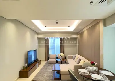 a living room with a couch and a tv at Sleek 2BR in Nobles, Business Bay in Dubai