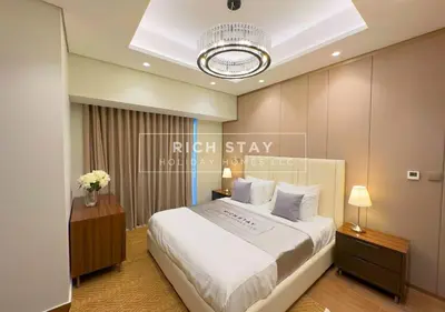 a bedroom with a large white bed and a chandelier at Sleek 2BR in Nobles, Business Bay in Dubai