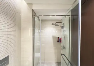 a shower with a glass door in a bathroom at Sleek 2BR in Nobles, Business Bay in Dubai