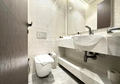 a white bathroom with a sink and a toilet at Sleek 2BR in Nobles, Business Bay in Dubai