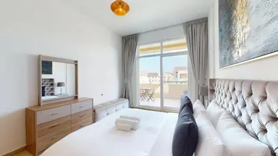 a bedroom with a large couch and a large window at Widcombe House - Tranquil One Bed in Motor City in Dubai
