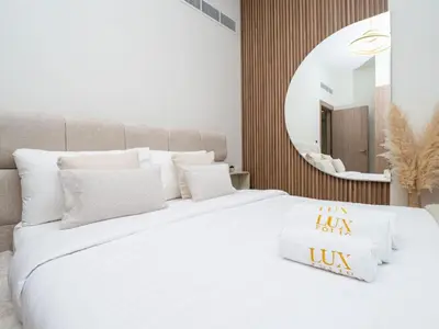 a bedroom with a large white bed with a mirror at Serene 1-Bedroom Retreat in Azizi Riviera with Calming Tones in Dubai