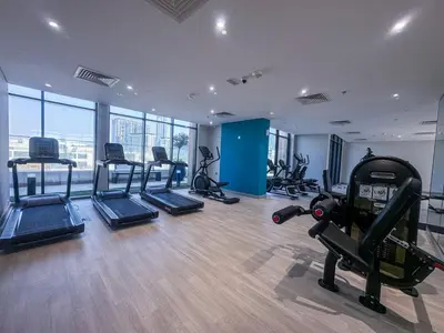 a gym with several treadmills and exercise bikes in it at Serene 1-Bedroom Retreat in Azizi Riviera with Calming Tones in Dubai