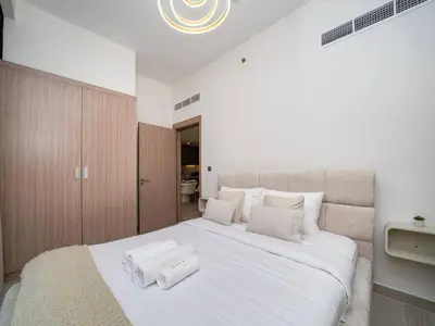 a bedroom with a large white bed with two towels on it at Serene 1-Bedroom Retreat in Azizi Riviera with Calming Tones in Dubai