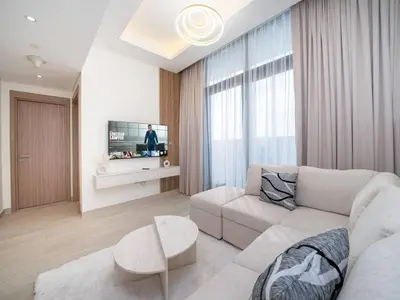 a living room with a couch and a tv at Serene 1-Bedroom Retreat in Azizi Riviera with Calming Tones in Dubai