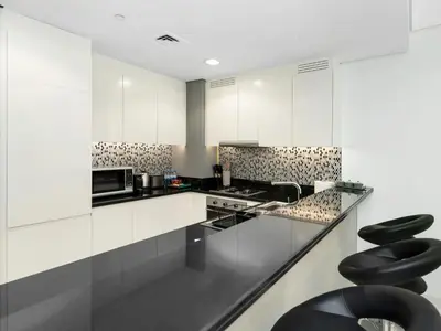 a kitchen with white cabinets and black stools at Famous Infinity Pool 64th floor near Burj Khalifa in Dubai