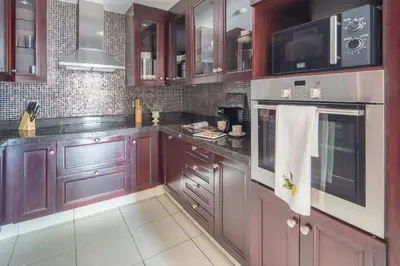a kitchen with brown wooden cabinets and a microwave at Frank Porter - Reehan 7 in Dubai