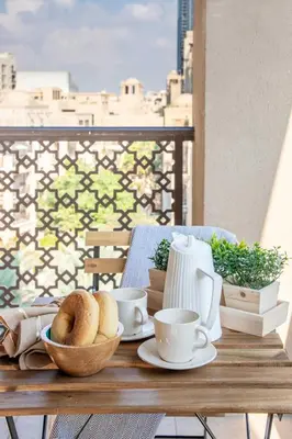a table with coffee cups and bread on a balcony at Frank Porter - Reehan 7 in Dubai