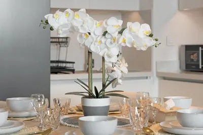 a table with a vase of white flowers on it at Amazing 2BR Home Burj Khalifa View Steps Walk to DubaiMall in Dubai