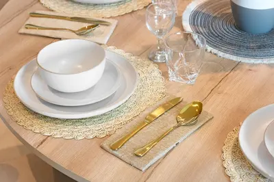 a wooden table with a white bowl and plates and silverware at Amazing 2BR Home Burj Khalifa View Steps Walk to DubaiMall in Dubai