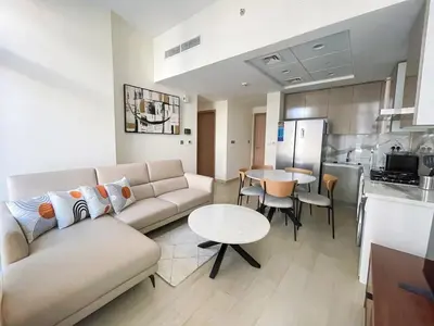 a living room with a couch and a table and a kitchen at Brand New Spacious 3-BedroomIAzizi Riviera 16 in Dubai