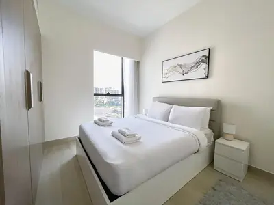 a white bedroom with a large bed and a window at Brand New Spacious 3-BedroomIAzizi Riviera 16 in Dubai