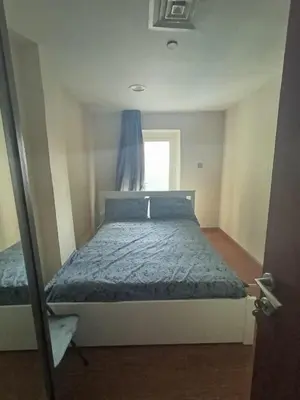 a bedroom with a bed with a blue comforter and a window at In the heart of Dubai in Dubai