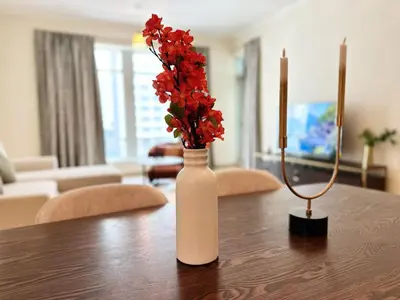 a white vase with red flowers on a table at Step into Sophistication - Stylish 1-BR Apartment in Downtown Dubai by petals Holiday Homes in Dubai