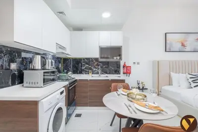 a kitchen and a living room with a table at Vogue Arjan Jwelz by Danube near Miracle and Butterfly Garden, Studio Apartment with Balcony and Vibrant Community View, Access to all Amenities in Dubai