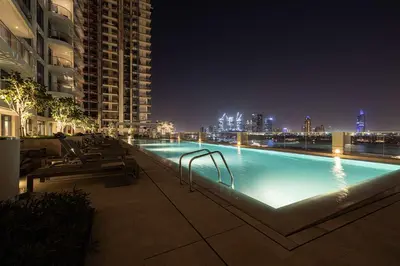 a swimming pool at night with a city skyline at Seaside Serenity 1Bd Beachfront Apartment in Dubai
