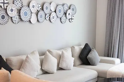 a white couch in a living room with plates on the wall at Seaside Serenity 1Bd Beachfront Apartment in Dubai