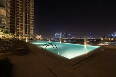 a swimming pool at night with a city skyline at Seaside Serenity 1Bd Beachfront Apartment in Dubai