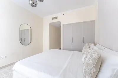 a white bedroom with a bed and a mirror at HAVN - 2 Bedroom in Marina Quays, Dubai Marina in Dubai
