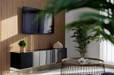 a living room with a table and a tv on a wall at Huge Sky Villa With Panoramic Golf Views in Dubai