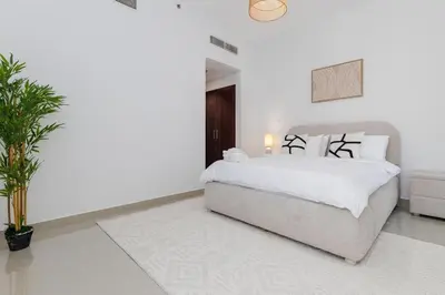 a white bedroom with a bed and a plant at Huge Sky Villa With Panoramic Golf Views in Dubai