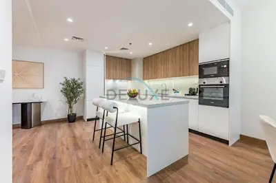 a white kitchen with a counter and stools at Revamped 1BR Unit with Partial Sea & Palm Jumeirah Views Close to Beach , Elite Residence, Dubai Marina by Deluxe Holiday Homes in Dubai