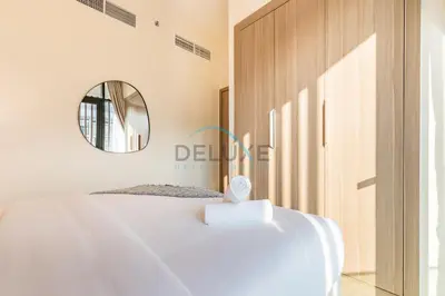 a bedroom with a white bed and a mirror at Pool Views 1BR Close to Major Landmarks in Azizi Riviera 18, Al Merkadh by Deluxe Holiday Homes in Dubai