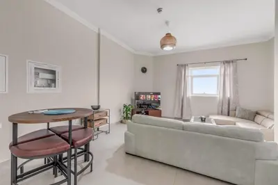 a living room with a couch and a table at Waves - Spacious 1BR with Balcony & Cozy Interiors in JVC in Dubai