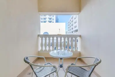 a table and two chairs in a room with a balcony at Waves - Spacious 1BR with Balcony & Cozy Interiors in JVC in Dubai