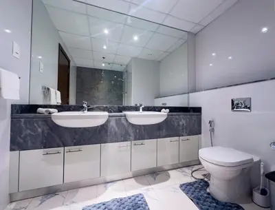 a bathroom with two sinks and a toilet at Luxury Meets Serenity 2BR Apt in Noura Tower in Dubai