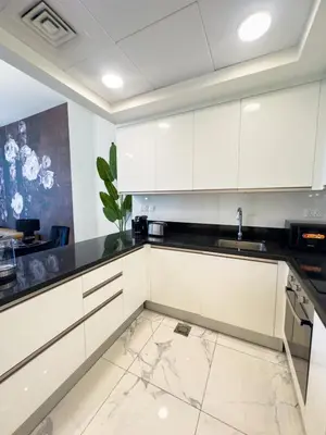 a kitchen with white cabinets and a marble floor at Luxury Meets Serenity 2BR Apt in Noura Tower in Dubai