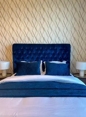 a bed with a blue headboard and two lamps at Luxury Meets Serenity 2BR Apt in Noura Tower in Dubai