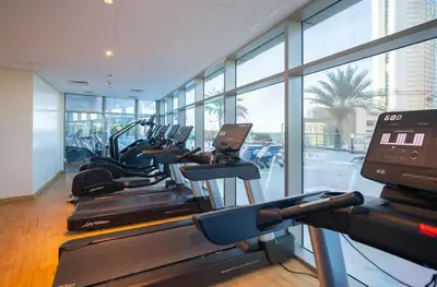 a gym with a row of treadmills and elliptical machines at 160M2 Modern 2-bedrooms apartment with fantastic views in Dubai