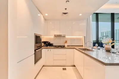 a kitchen with white cabinets and a large window at FAM Living - Samana Park Views - Brandnew 1Bed in Dubai