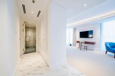 a hallway with a blue chair and a television at Cheval Maison - Expo City Dubai in Dubai